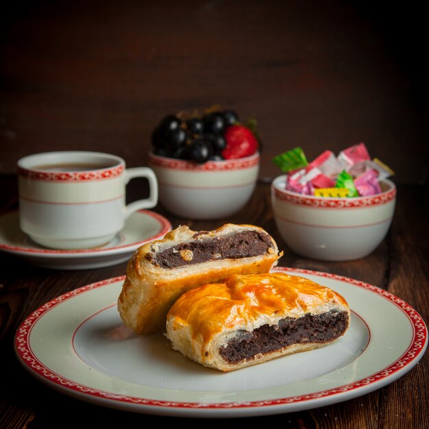 Close-up homemade bakery with cup of tea, candies and berries on wooden table