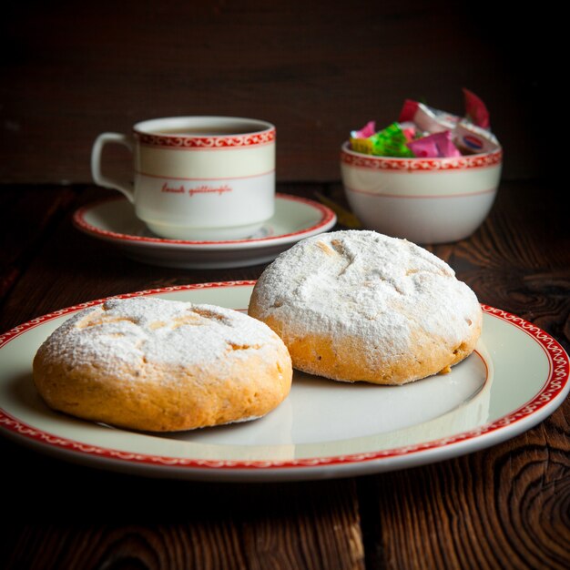 Close-up homemade cookies with cup of tea and candies on wooden table