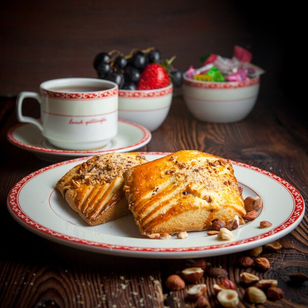 Close-up homemade cookies with cup of tea and candies on wooden table