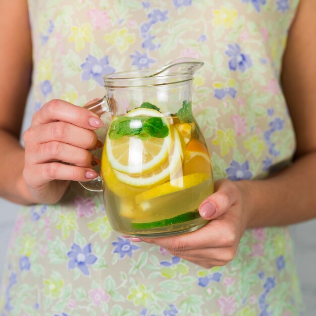 Close up homemade lemonade jug held by woman