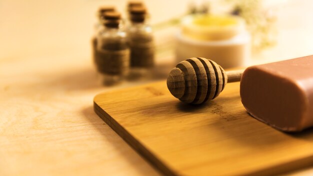 Close-up of honey dipper and herbal soap on wooden board