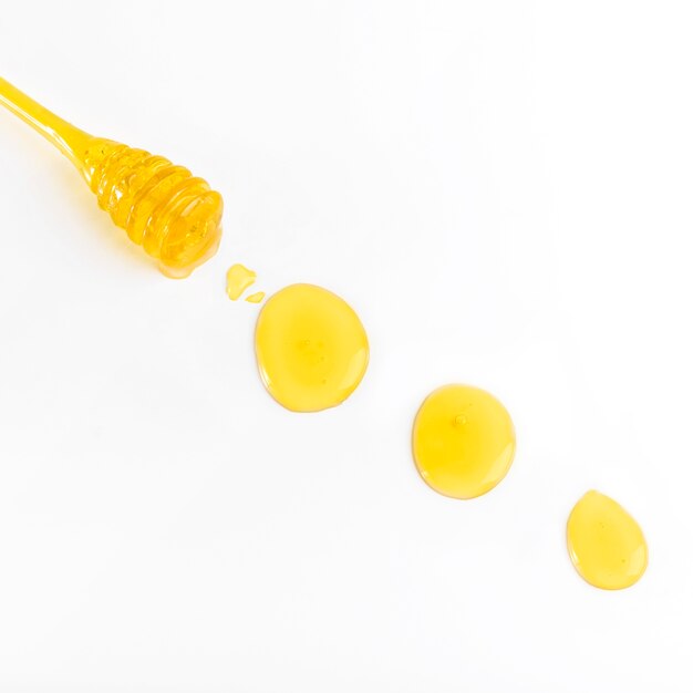 Close-up of honey and dipper on white background