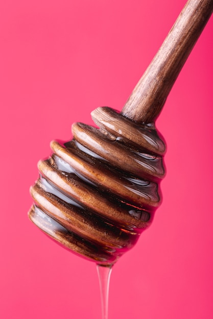 Close up honey dripping off wooden dipper