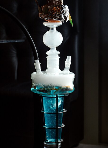 close up of hookah with fruits in blue water