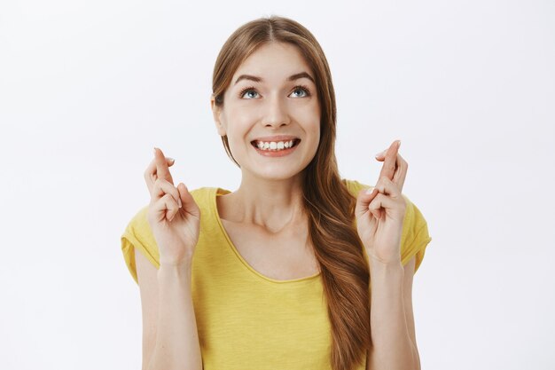 Close-up of hopeful smiling woman making wish, dreaming over white background