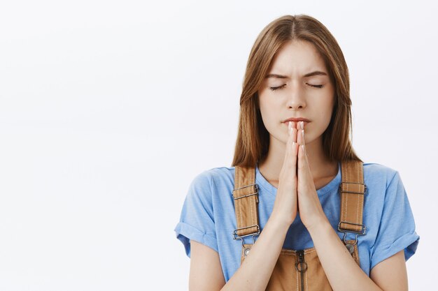 Close-up of hopeful young woman praying, pleading god, making wish