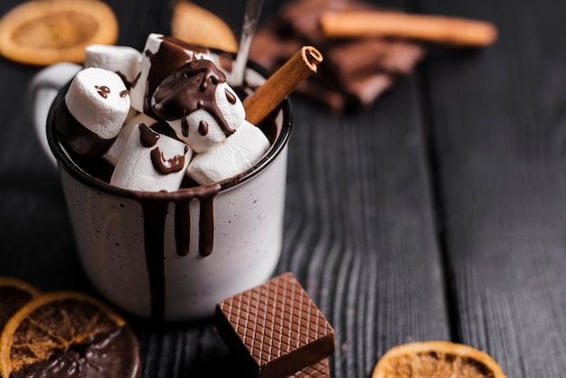 Foto gratuita chiuda su cioccolata calda con il bastoncino di cannella delle caramelle gommosa e molle e le fette arancio secche