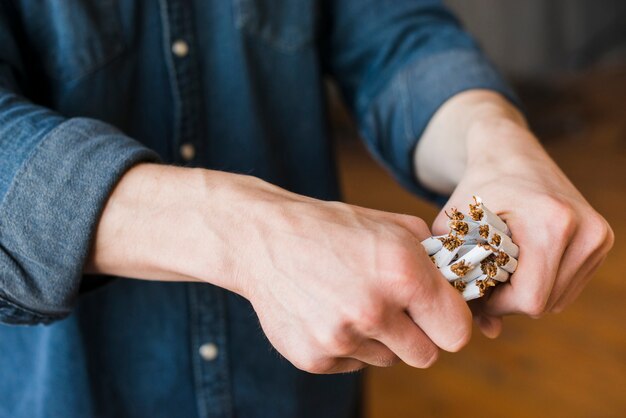 Close-up of human hand breaking bundle of cigarettes
