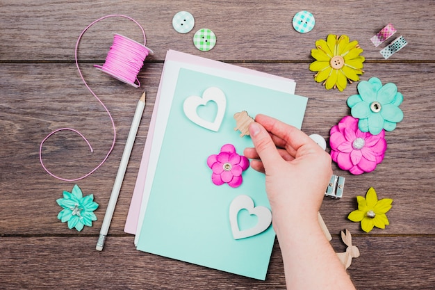 Close-up of human hand decorating the greeting card on wooden desk