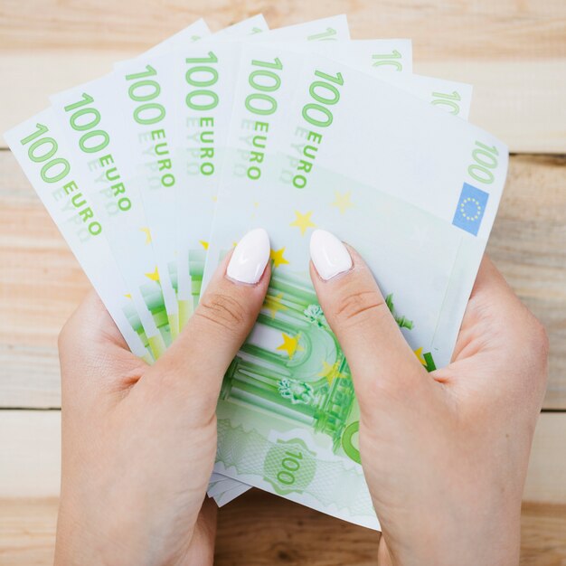 Крупным планом рука человека, сто банкнот евро на деревянный стол