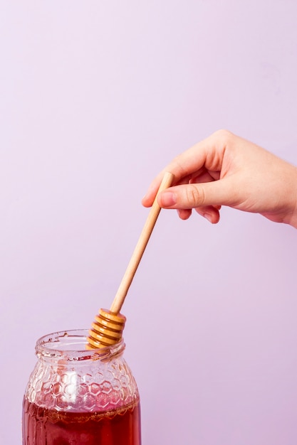 Free photo close-up of human hand picking honey from jar