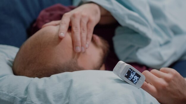 Close up of ill man with headache using oximeter