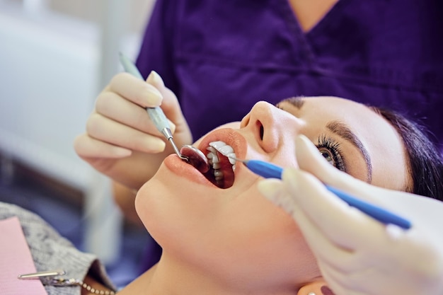 歯科で女性の歯を調べている歯科医のクローズアップ画像。
