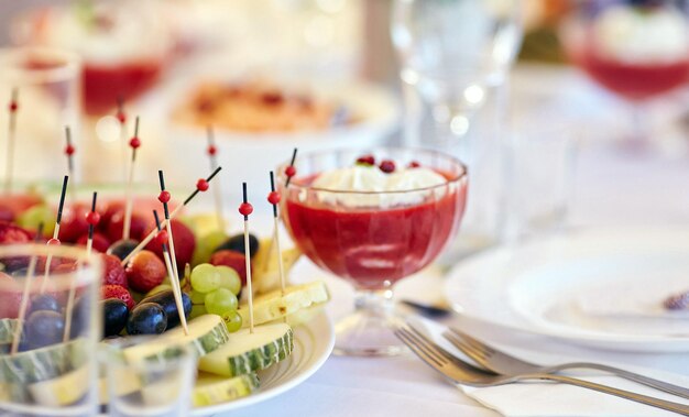 Close-up image of a festive table with sliced fruits and desserts. Festive event, party or wedding reception.