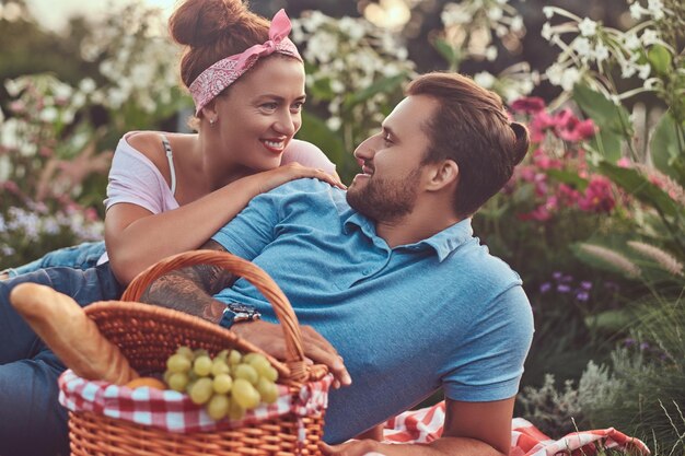 Close-up image of a happy middle age couple during romantic dating outdoors, enjoying a picnic while lying on a blanket in the park.