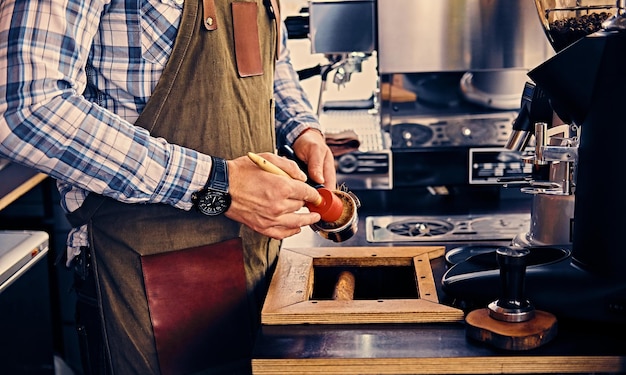 Close up image of a man cleans coffee machine with a tassel.