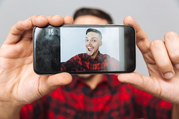 Close up image of man making photo on smartphone