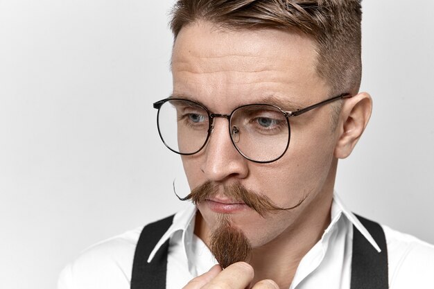 Close up image of stylish handsome pensive unshaven male entrepreneur