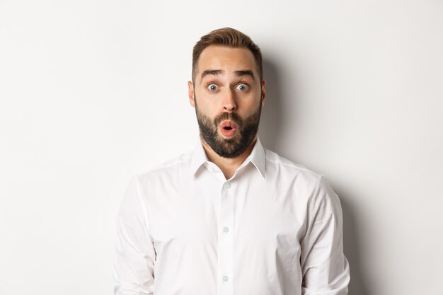 Close-up of impressed man saying wow, looking amazed at camera, standing  