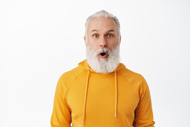 Close up of impressed senior hipster gasping saying wow bearded old man drop jaw and staring in awe at camera checking out awesome advertisement big promo deal white background