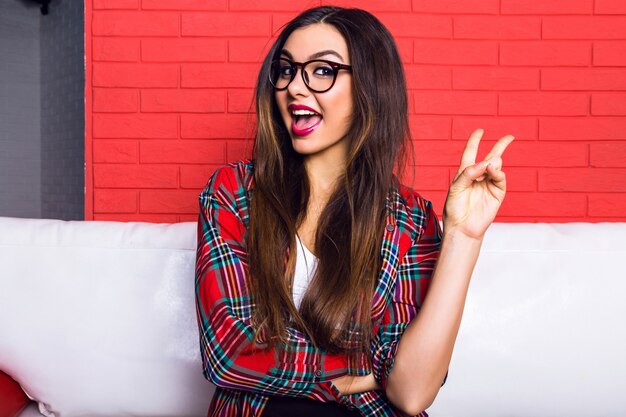 Close up indoor portrait of young pretty hipster woman with long brunette hairs and bright make up