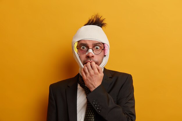 Close up on injured man with dark bruise under eyes and brain concussion, wears bandage