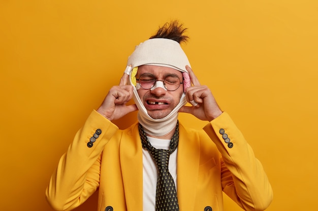 Close up on injured man with dark bruise under eyes and brain concussion, wears bandage