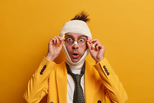 Close up on injured man with dark bruise under eyes and brain concussion, wears bandage