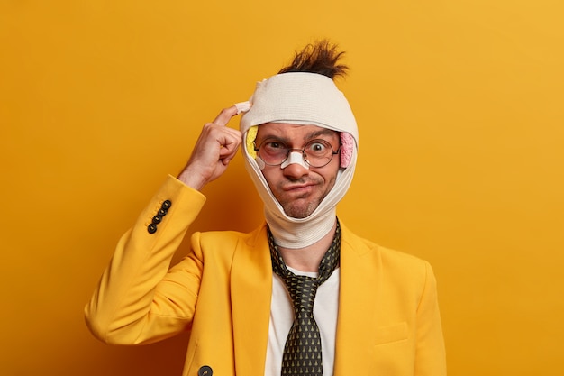 Close up on injured man with dark bruise under eyes and brain concussion, wears bandage