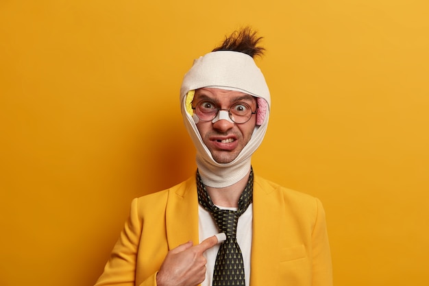 Close up on injured man with dark bruise under eyes and brain concussion, wears bandage