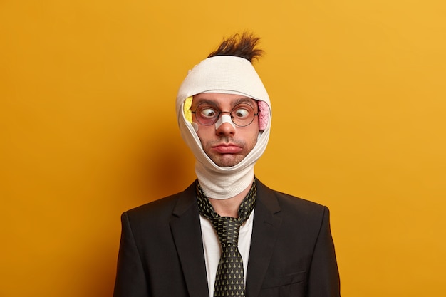 Close up on injured man with dark bruise under eyes and brain concussion, wears bandage