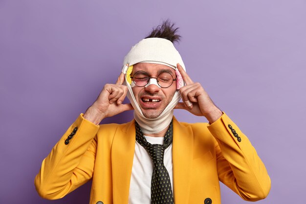 Close up on injured man with dark bruise under eyes and brain concussion, wears bandage