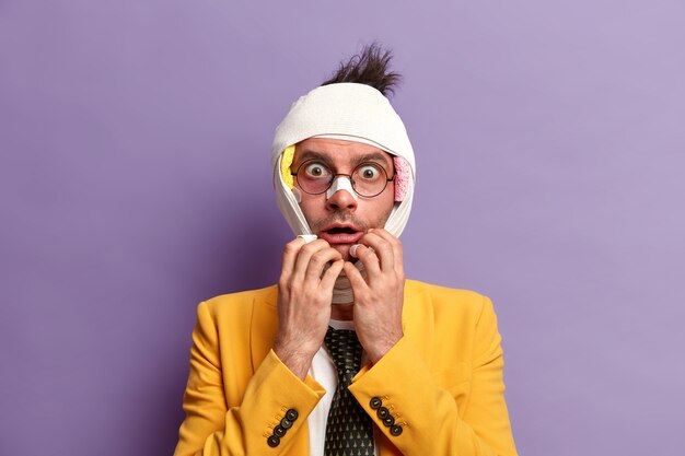 Close up on injured man with dark bruise under eyes and brain concussion, wears bandage