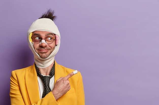 Close up on injured man with dark bruise under eyes and brain concussion, wears bandage