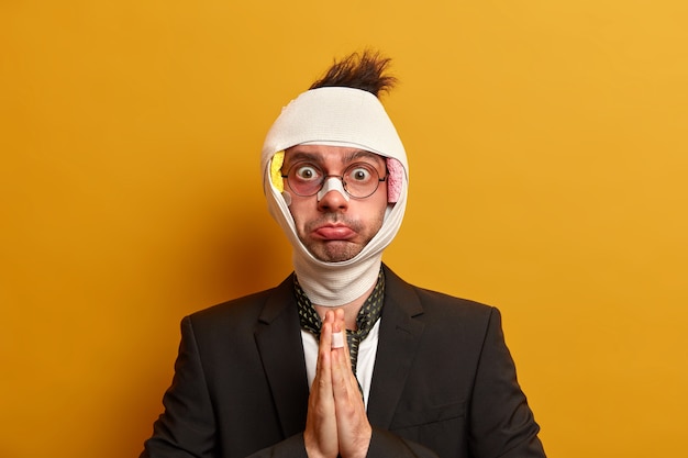 Close up on injured man with dark bruise under eyes and brain concussion, wears bandage