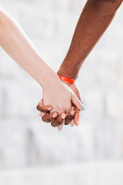 手を繋いでいる異人種間のカップルのクローズアップ