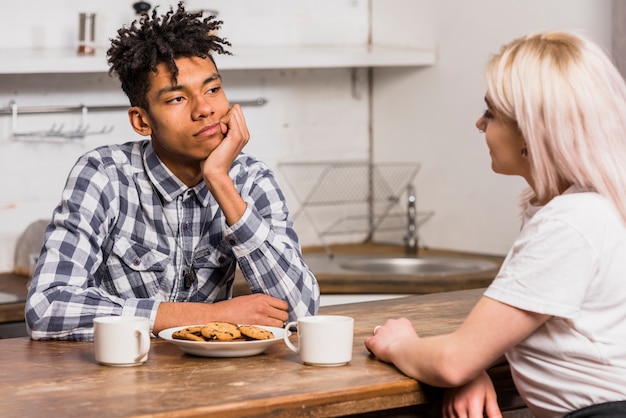 Close-up of interracial young couple looking at each other while having breakfast