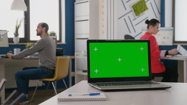 Close up of isolated green screen on laptop at empty desk. Device with mock up template and chroma key background on display. Computer with chroma-key and mockup app on screen.