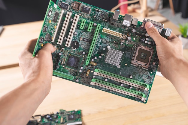 Close-up of IT male technician holding computer mainboard