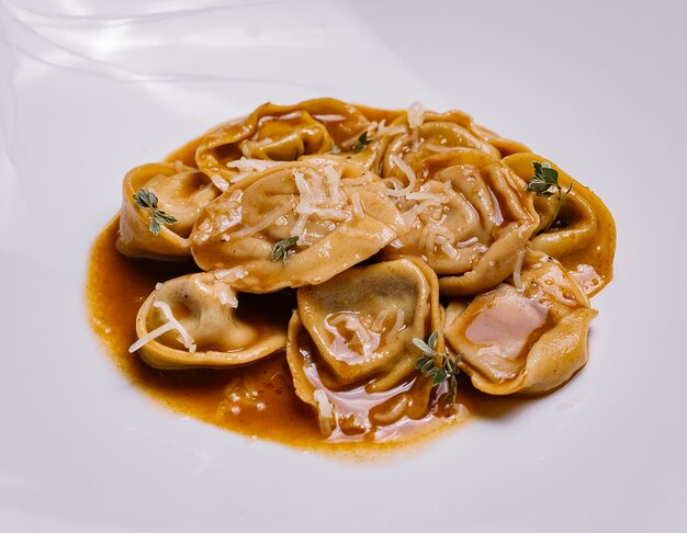 Close up of italian dumpling pasta in sauce garnished with parmesan