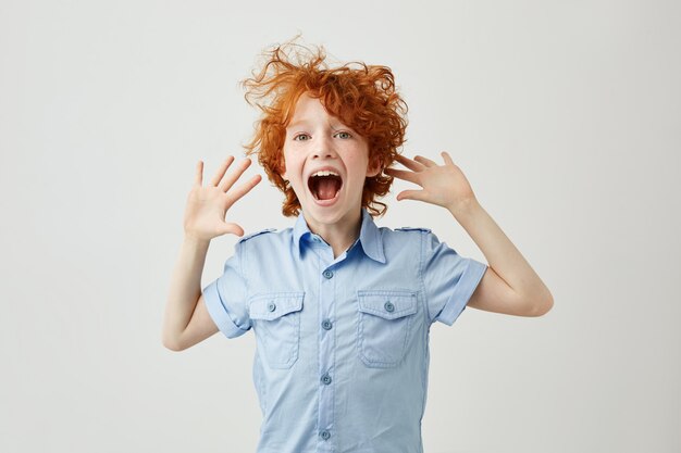 Close up of joyful little ginger boy with freckles jumping and having fun