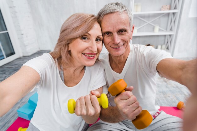 Close-up of joyful loving senior couple exercising with dumbbells