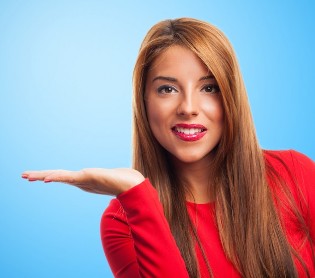 Close-up of joyful woman showing open hand on blue background