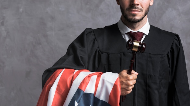 Close-up  judge in robe holding gavel and flag