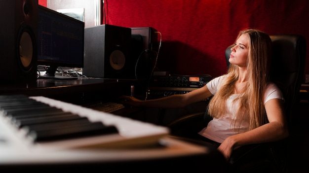クローズアップキーボードとスタジオでぼやけている女性