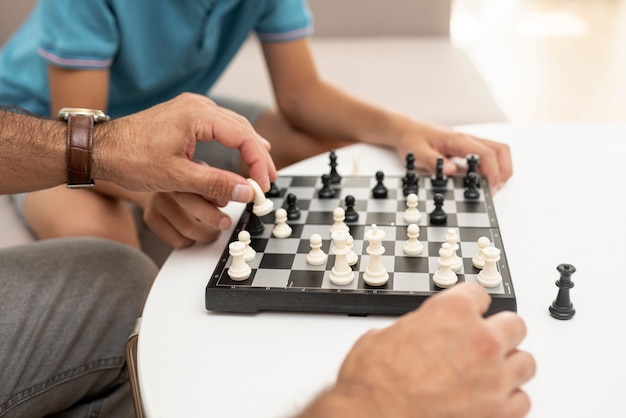 Close-up kid and adult playing chess