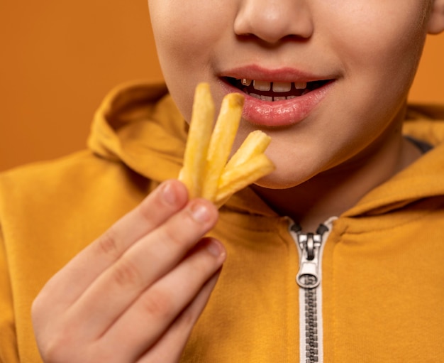 Bambino del primo piano che mangia patatine fritte