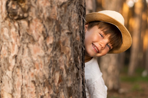 Free photo close-up kid hiding behind tree