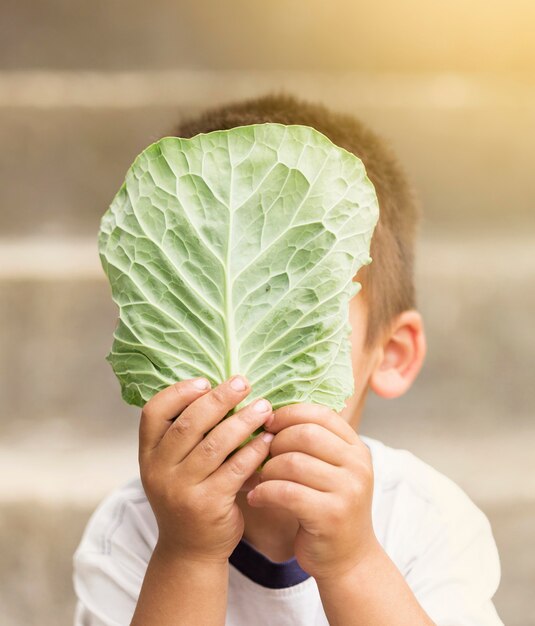 Малыш крупным планом держит лист салата