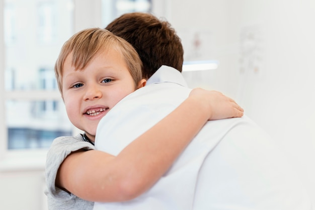 Close-up kid hugging doctor